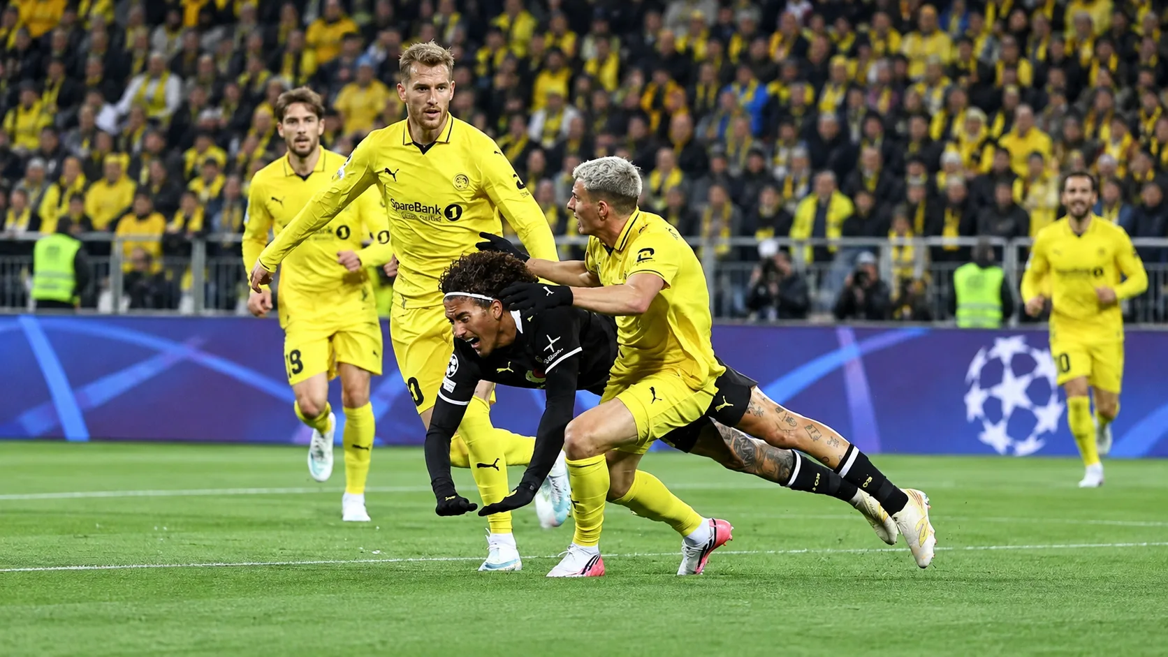 Vue large derrière un but sur la pelouse et des joueurs de Bodø/Glimt et Dortmund dispersés après le match.
