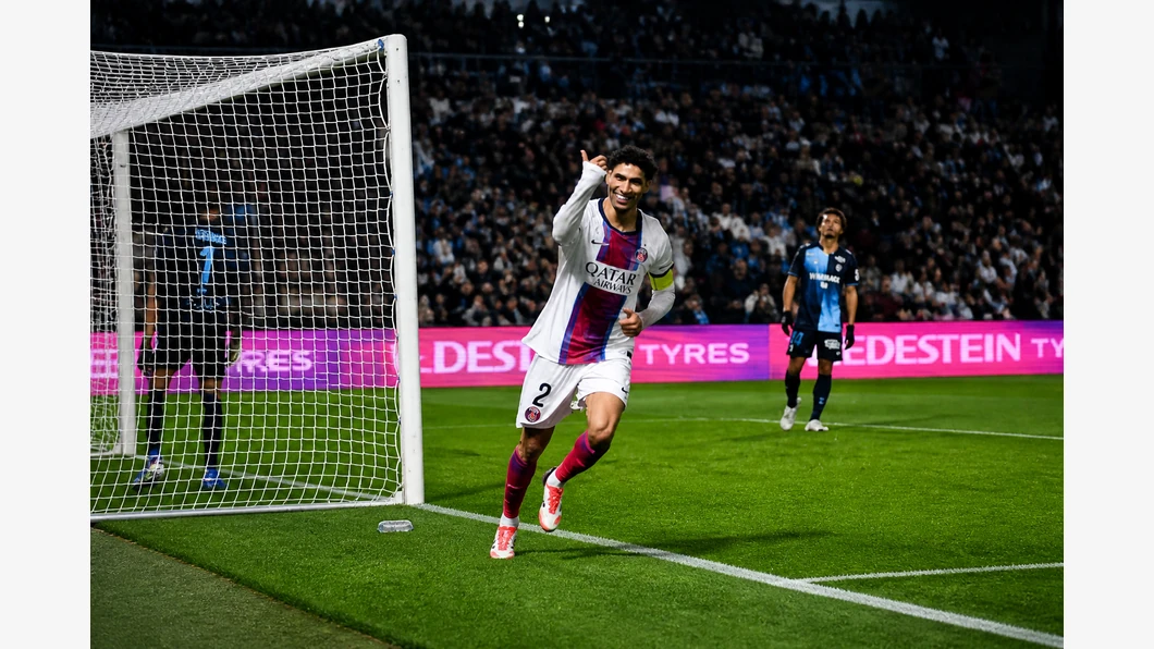Josh Maja du Havre AC et Achraf Hakimi du PSG se disputent le ballon au premier plan devant des tribunes floutées.