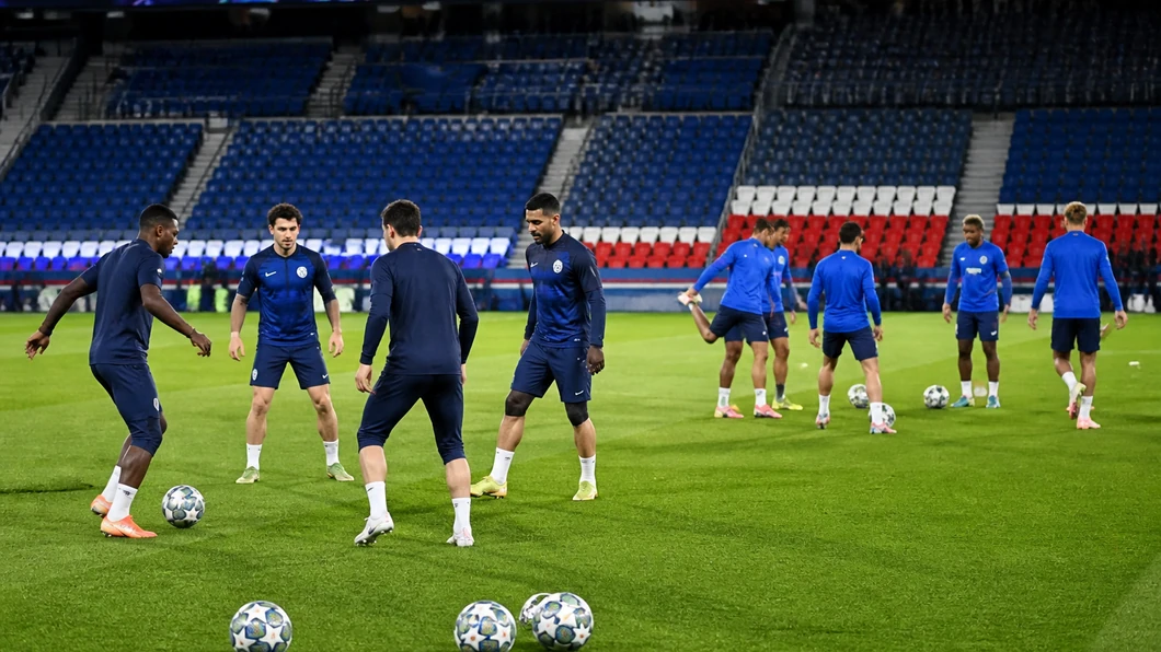 Joueurs du Paris Saint-Germain et du FC Barcelona s’échauffent séparément sur la pelouse, entre passes courtes et étirements.