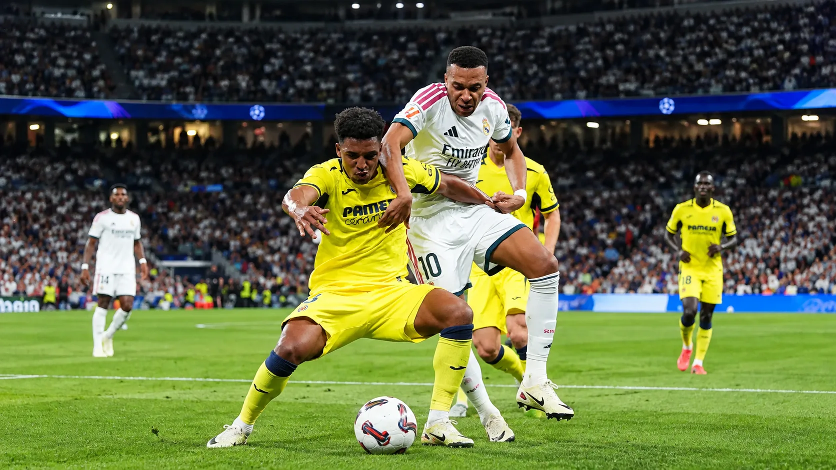 Deux joueurs en blanc et en jaune évoluent dans une phase de jeu calme sur la pelouse.