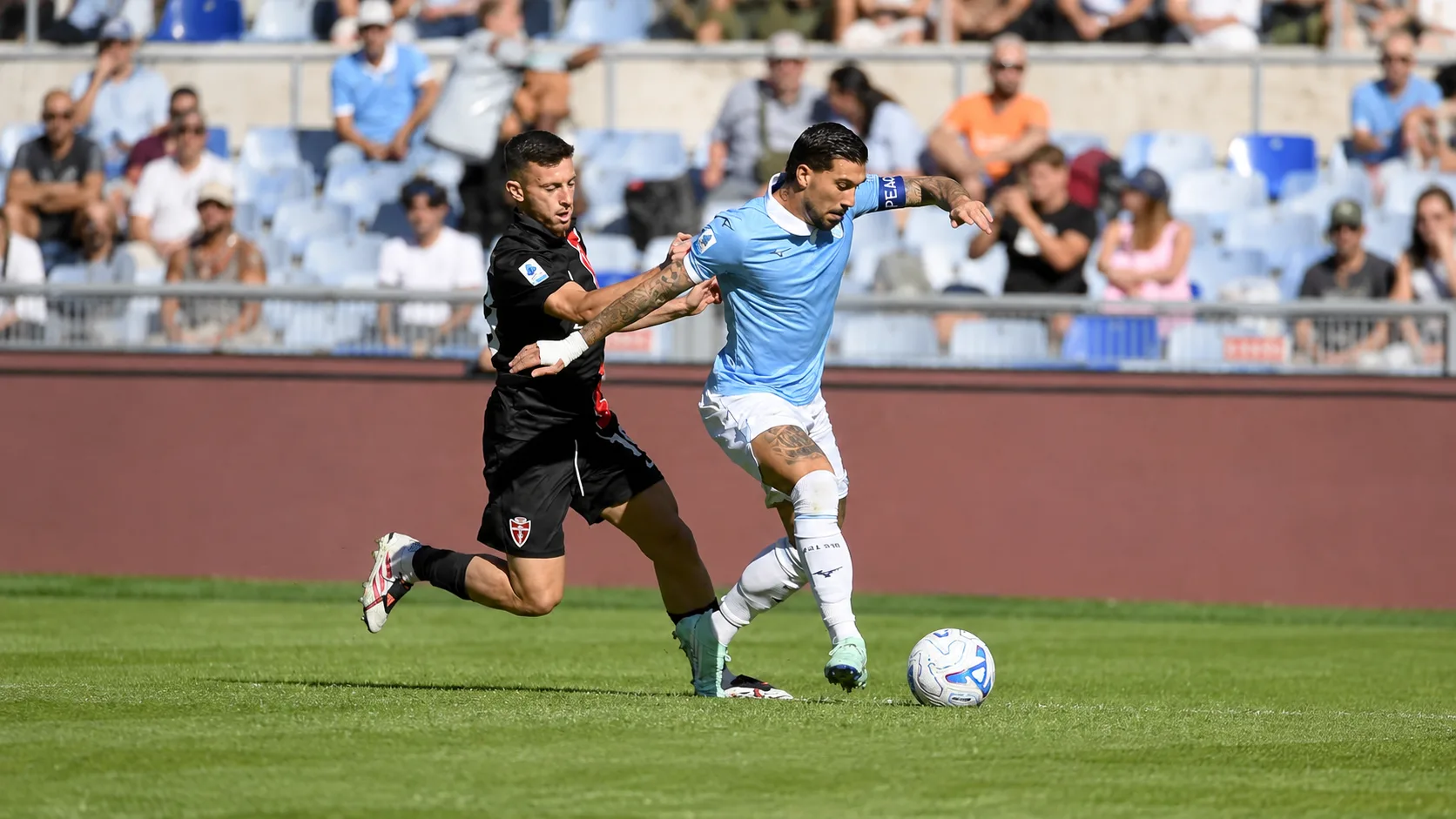 Joueurs de la Lazio et de Monza se replacent sur le terrain, avec un ballon près de la ligne médiane.