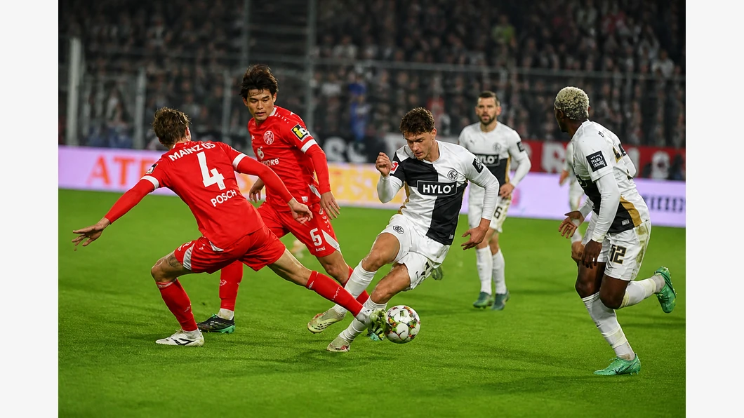Felix Keidel d’Elversberg et Nadiem Amiri de Mainz luttent pour le ballon au premier plan devant des tribunes floutées.
