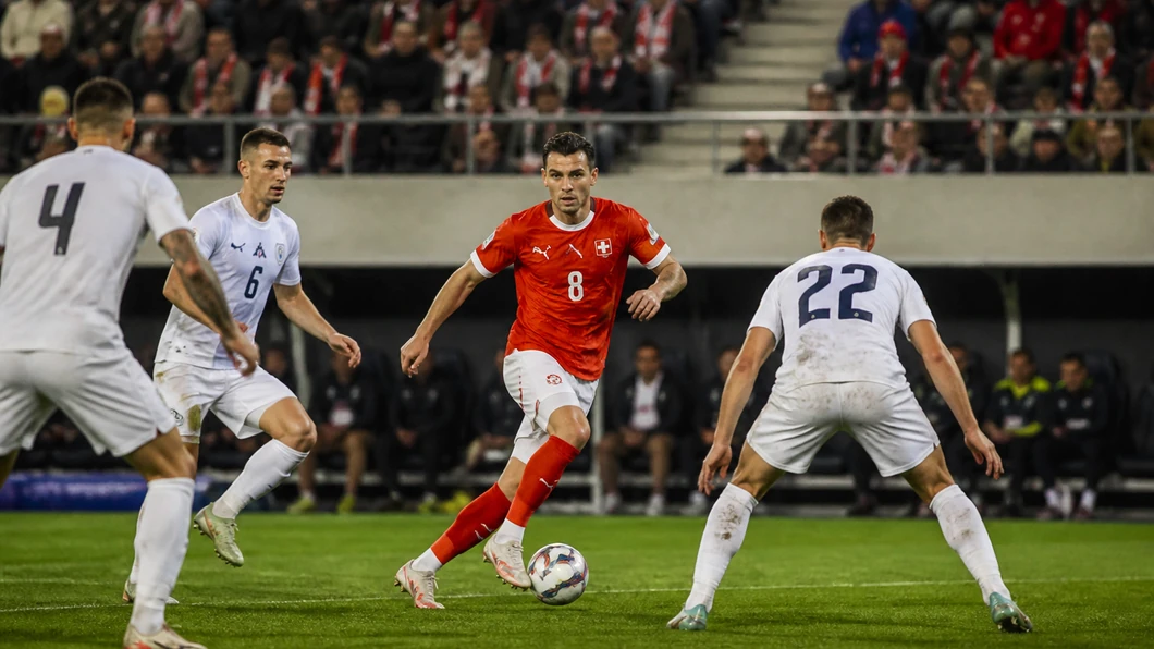 Un joueur suisse progresse face à la défense slovène dans un match de Ligue des Nations.