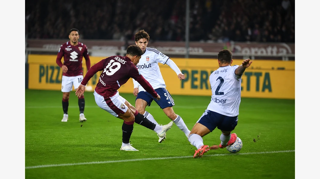 Che Adams du Torino FC et Nico Paz de Como 1907 se disputent le ballon au premier plan devant des tribunes flout&eacute;es.