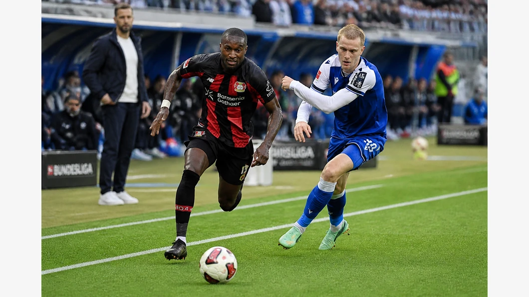 Andrej Kramarić de Hoffenheim et Edmond Tapsoba de Leverkusen se disputent le ballon au premier plan.